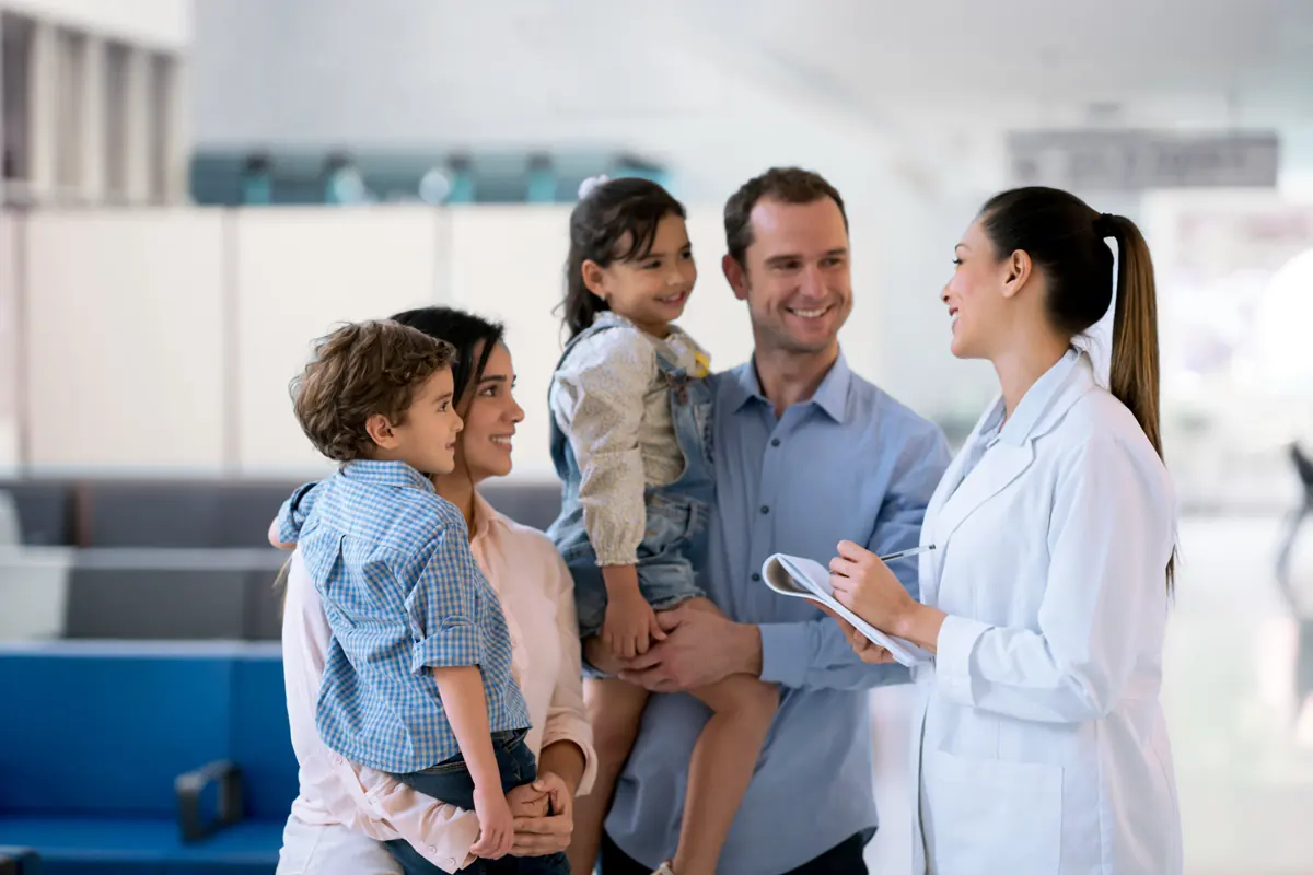 Familia con dos hijos conversando con una doctora en un centro médico